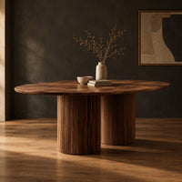 Oval dining table with two fluted cylinder bases in a dark studio against a charcoal plaster wall
