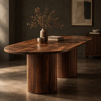 Corner detail of oval dining table with two fluted cylinder bases beside wood, brass and linen samples