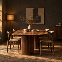 Oval dining table with two fluted cylinder bases in a dark dining room at golden hour