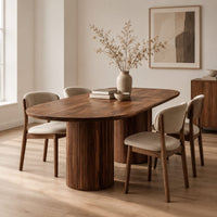 Oval dining table with two fluted cylinder bases in a Scandinavian dining room with white walls