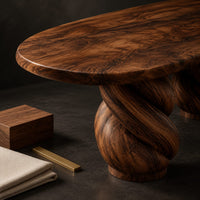 Corner detail of oval dining table with two twisted rope pedestal bases beside wood, brass and linen samples
