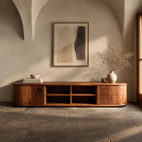 Corner detail of oval ended tv stand with four open cubbies between two end cabinets beside wood, brass and linen samples