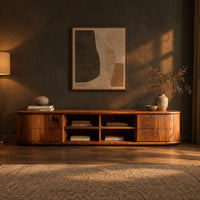 Oval ended tv stand with four open cubbies between two end cabinets in a dark living room at golden hour