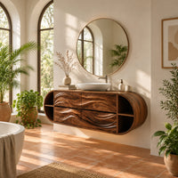 Oval floating cabinet with four carved wave panels and open end shelves in a bright bathroom with arched windows and plants