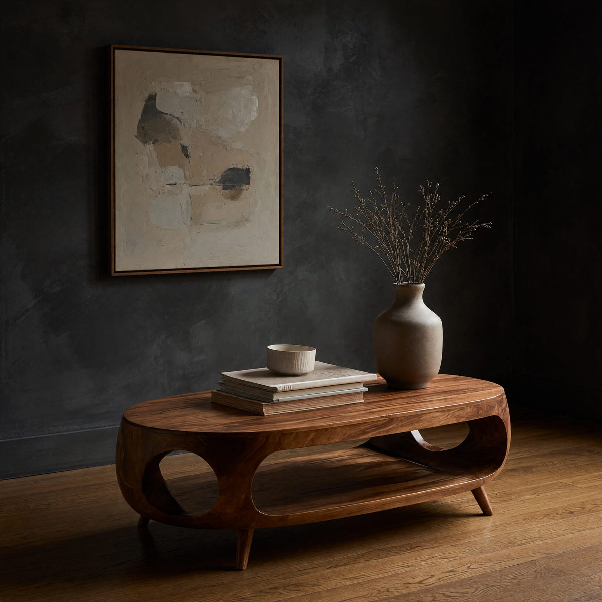 Oval porthole coffee table with a low shelf in a dark studio against a charcoal wall