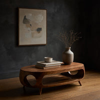 Oval porthole coffee table with a low shelf in a dark studio against a charcoal wall