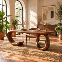 Oval top wooden desk with an open sweeping leg and a ring shaped base in a bright home office with arched windows and plants