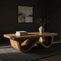 Pale hardwood coffee table with an undulating base, three-quarter view showing the grain