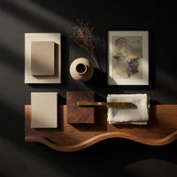 Corner detail of pale hardwood coffee table with an undulating base beside wood, brass and linen samples