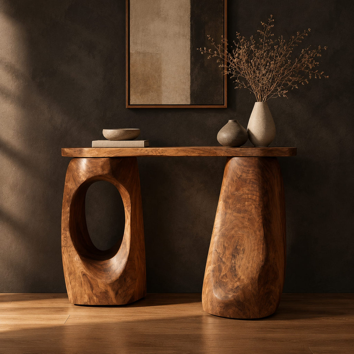Console table with two chunky pebble shaped legs and a slim oval ended top in a dark studio against a charcoal plaster wall