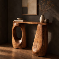 Corner detail of console table with two chunky pebble shaped legs and a slim oval ended top beside wood, brass and linen samples