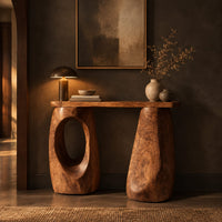 Console table with two chunky pebble shaped legs and a slim oval ended top in a dark entryway at golden hour