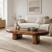 Pebble shaped coffee table with a smooth organic top and two thick column legs in a Scandinavian living room with white walls