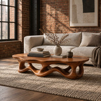Low oval coffee table with a wavy base cut through by irregular openings in an industrial loft living room with exposed brick