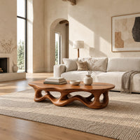 Low oval coffee table with a wavy base cut through by irregular openings in a bright open plan living room