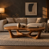Pebble shaped coffee table on branching legs with open arches in a dark living room at golden hour
