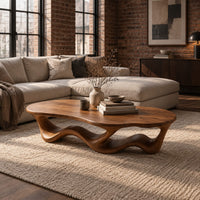 Pebble shaped coffee table with a rippling open ribbon base in an industrial loft living room with exposed brick