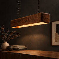 Long wood beam pendant light with soft corners and a warm glow below, three-quarter view showing the grain