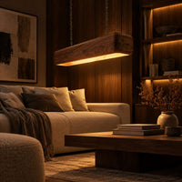 Long wood beam pendant light with soft corners and a warm glow below in an evening living room with walnut wall paneling