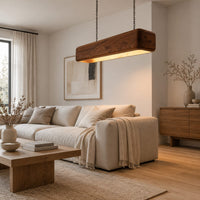 Long wood beam pendant light with soft corners and a warm glow below in a Scandinavian living room with white walls