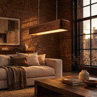 Long wood beam pendant light with soft corners and a warm glow below in an industrial loft living room with exposed brick
