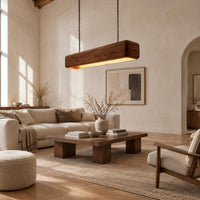 Long wood beam pendant light with soft corners and a warm glow below in a bright open plan living room