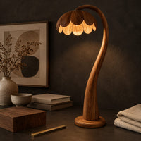 Corner detail of floor lamp with a flower petal shade on a slender arching stem beside wood, brass and linen samples