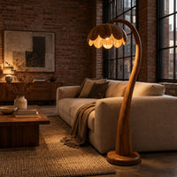 Floor lamp with a flower petal shade on a slender arching stem in an industrial loft living room with exposed brick