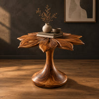End table with a carved petal top on a flaring trumpet shaped pedestal in a dark studio against a charcoal plaster wall