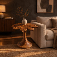 End table with a carved petal top on a flaring trumpet shaped pedestal in a dark living room at golden hour
