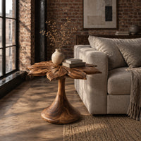 End table with a carved petal top on a flaring trumpet shaped pedestal in an industrial loft living room with exposed brick