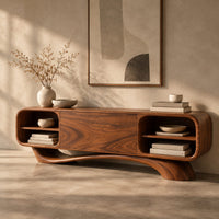 Corner detail of low pill shaped media cabinet with open end shelves on a sweeping wave base beside wood, brass and linen samples