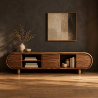 Pill shaped tv stand with open shelf bays and panel fronts in a dark studio against a charcoal plaster wall