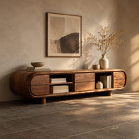 Corner detail of pill shaped tv stand with open shelf bays and panel fronts beside wood, brass and linen samples