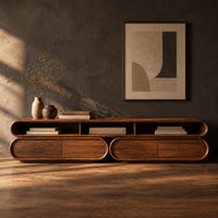 Corner detail of pill shaped tv stand with three open top bays and two lower cabinets beside wood, brass and linen samples