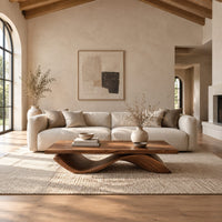 Rectangular coffee table with a flat plank top on a single rolling wave base in a bright open plan living room