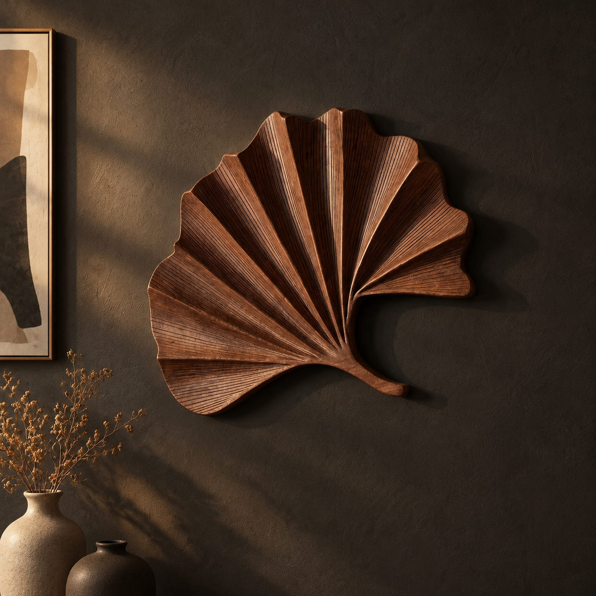 Fan shaped leaf wall art with carved radiating ridges and a curled stem on a dark charcoal plaster wall