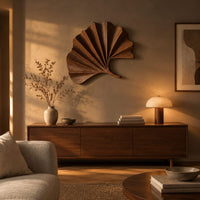 Fan shaped leaf wall art with carved radiating ridges and a curled stem above a low console in an evening living room