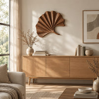 Fan shaped leaf wall art with carved radiating ridges and a curled stem above a light oak sideboard in daylight