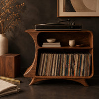 Corner detail of flared record stand with a small upper bay and a larger open bay below beside wood, brass and linen samples