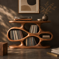 Corner detail of sculpted record player stand with flowing open cutouts and a flat top beside wood, brass and linen samples