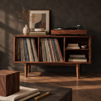 Corner detail of open record player stand with four bays on tapered legs beside wood, brass and linen samples