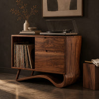 Corner detail of record player stand with an open side bay and a sweeping ribbon base beside wood, brass and linen samples