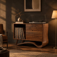 Record player stand with an open side bay and a sweeping ribbon base in a dark living room at golden hour