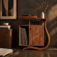 Corner detail of record player stand with a ribbon base, a side slot and a raised top beside wood, brass and linen samples