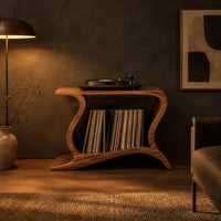 Record player stand with wave shaped sides and a wide open shelf in a dark living room at golden hour