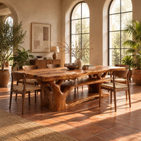 Rectangle dining table on a branching tree trunk base in a bright dining room with arched windows and plants