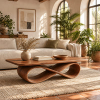 Rectangular wooden coffee table on a figure eight ribbon base in a bright living room with arched windows and plants