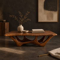 Corner detail of rectangular coffee table with a slab top and branching arched base beside wood, brass and linen samples