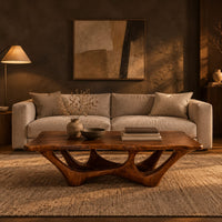 Rectangular coffee table with a slab top and branching arched base in a dark living room at golden hour